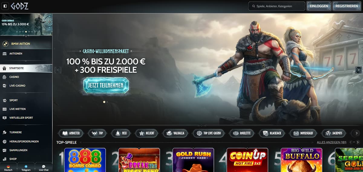 Godz Startseite mit Banner, das ein Willkommenspaket von 100 % bis zu 2.000 € plus 300 Freispiele bewirbt. Design im Mythologie-Stil mit Kriegerfiguren vor Bergen. Seitenleiste umfasst Casino, Live-Casino, Sportwetten und Turniere. Bereich zeigt Slots wie Break the Bank Again, Gold Rush Johnny Cash und Big Wild Buffalo.